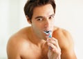 Hygiene - Handsome young guy brushing his teeth. Portrait of a young masculine man brushing his teeth. Royalty Free Stock Photo