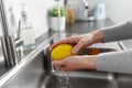 Close up of woman washing lemon fruit in kitchen