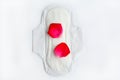 Hygiene during menstruation in women. Sanitary napkin with red rose petals on a white background