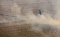 Hyogo, Japan - February 5, 2023: Smoke rises around masked man during controlled burn on dry fields at farm