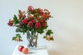 Hypericum and hawthorn flowers in vase on a white stool on a white background Royalty Free Stock Photo