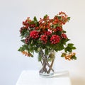 Hypericum and hawthorn flowers in vase on a white stool on a white background Royalty Free Stock Photo