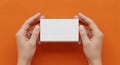 Hyperrealistic Blank White Business Card Stack Mockup Held by Female Hands Against a Vibrant Orange Studio Background Royalty Free Stock Photo