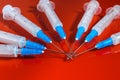 Hypodermic syringe. Syringes with blue needles on a red background. Medical Injectors.