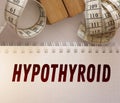 Hypothyroid word on page of copybook and measurement tape besides. Thyroid hormane causes overweight. Healthcare concept Royalty Free Stock Photo