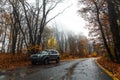 Hyundai Tucson SUV car on wet asphalt road passing through colorful autumn forest