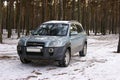 Hyundai Tucson SUV on the road in a pine winter forest