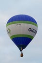 A colourful hot air balloon with advertisement flying high in the summer sky