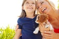 I adore my little girl. a little girl holding a puppy while her mother smiles at her lovingly.