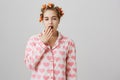 Am I already pretty. Portrait of funny cute caucasian girl at home, wearing hair curlers, trying to create beautiful Royalty Free Stock Photo