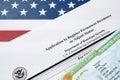 I-485 Application to register permanent residence or adjust status form and green card from dv-lottery lies on United States flag