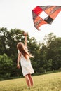 I believe I can fly. Happy girl in white clothes have fun with kite in the field. Beautiful nature Royalty Free Stock Photo