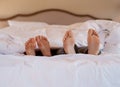 I belong next to you. Shot of an unrecognizable couples feet poking out under the sheets while lying in bed.