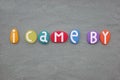I came by, creative slogan composed with multi colored stone letters over green sand