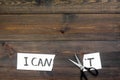 I can concept. Encourage youself. Sciccors cut off the letter t of written word I can`t. Dark wooden background top view Royalty Free Stock Photo