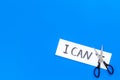 I can concept. Motivate youself, believe in yourself. Sciccors cut the letter t of written word I can`t. Blue background Royalty Free Stock Photo