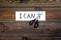 I can concept. Motivate youself, believe in yourself. Sciccors cut the letter t of written word I can`t. Dark wooden Royalty Free Stock Photo