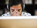 I can do this if I put my mind to it. Closeup shot of a stressed out young man working on a computer while listening to Royalty Free Stock Photo