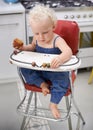 I can feed myself. A happy little baby eating solid food while sitting on a high chair. Royalty Free Stock Photo