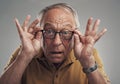 I can see clearly now. Studio shot of an elderly man adjusting his spectacles against a grey background. Royalty Free Stock Photo