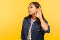 I can`t hear! Portrait of girl in denim shirt holding hand near ear, listening attentively with interest private conversation