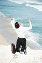 I cant do this anymore. Businessman kneeling on a cliff overlooking the ocean with his hands in the air.