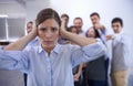 I cant hear you. a stressed young woman trying to block out her coworkers taunts.