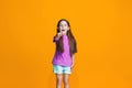 The happy teen girl pointing to you, half length closeup portrait on orange background.