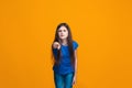 The happy teen girl pointing to you, half length closeup portrait on orange background. Royalty Free Stock Photo