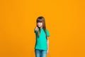 The happy teen girl pointing to you, half length closeup portrait on orange background. Royalty Free Stock Photo