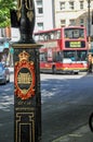 I colorful sign on a lamppost in central London, UK, highlighting the City of Westminster, with a classic red double-decker bus in