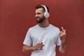 I am cool. Portrait of happy handsome man in headphones listening to the music and smiling while standing against red Royalty Free Stock Photo