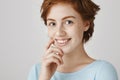 I am curious with your offer. Studio portrait of cute charismatic european ginger girl with freckles smiling broadly Royalty Free Stock Photo