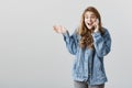 I did not believe it too. Excited happy feminine girl with blonde hair talking on smartphone, gesturing with raised palm Royalty Free Stock Photo