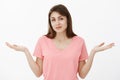 I do not know. Portrait of unaware clueless woman in pink t-shirt, shrugging with spread palms and slight smile, being