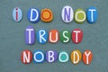 I do not trust nobody, negative slogan composed with multi colored stone letters over green sand