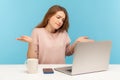 I don`t know! Confused woman raising arms in questioning gesture and looking at laptop screen, talking on video call Royalty Free Stock Photo