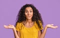 I Don`t Know. Doubtful Brunette Woman Shrugging Shoulders Over Purple Studio Background Royalty Free Stock Photo