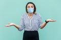 I don`t know what to do. Portrait of confused middle aged woman with surgical medical mask standing with raised arms and thinking