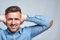 I don't wanna hear you. Depressed man closing ears with both hands and screaming while standing against grey background Royalty Free Stock Photo
