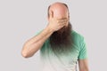 I don`t want to look at this. Portrait of scared or shocked middle aged bald man with long beard in light green t-shirt standing