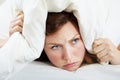 I dont wanna get up. A grumpy looking woman lying in bed with a pillow over her head.