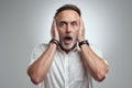 I dont wanna hear it. Studio portrait of a mature man covering his ears and looking shocked against a grey background.