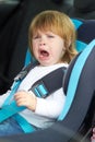 I dont wanna sit here Let me out. Portrait of a young baby crying while strapped into a car seat.