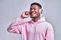 I enjoy the music!Young handsome african american man holds stylish silver earphones and smiles while looking at free space on a Royalty Free Stock Photo