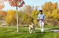 I enjoy the walks more than my dog does. a young man taking his dog for a walk through the park. Royalty Free Stock Photo