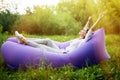 I am free. Pretty young woman lying on inflatable sofa lamzac with reised hands in the air while resting on grass in park Royalty Free Stock Photo