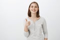 I give idea thumbs up. Pleased happy charming young european woman with short brown hair smiling with cheerful