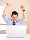 I got the contract. Excited young businessman in front of his laptop with his arms raised. Royalty Free Stock Photo