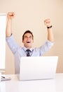 I got the deal. Excited young businessman in front of his laptop with his arms raised. Royalty Free Stock Photo